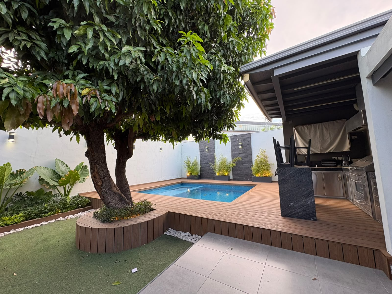 Deck sintético alrededor de alberca y árbol