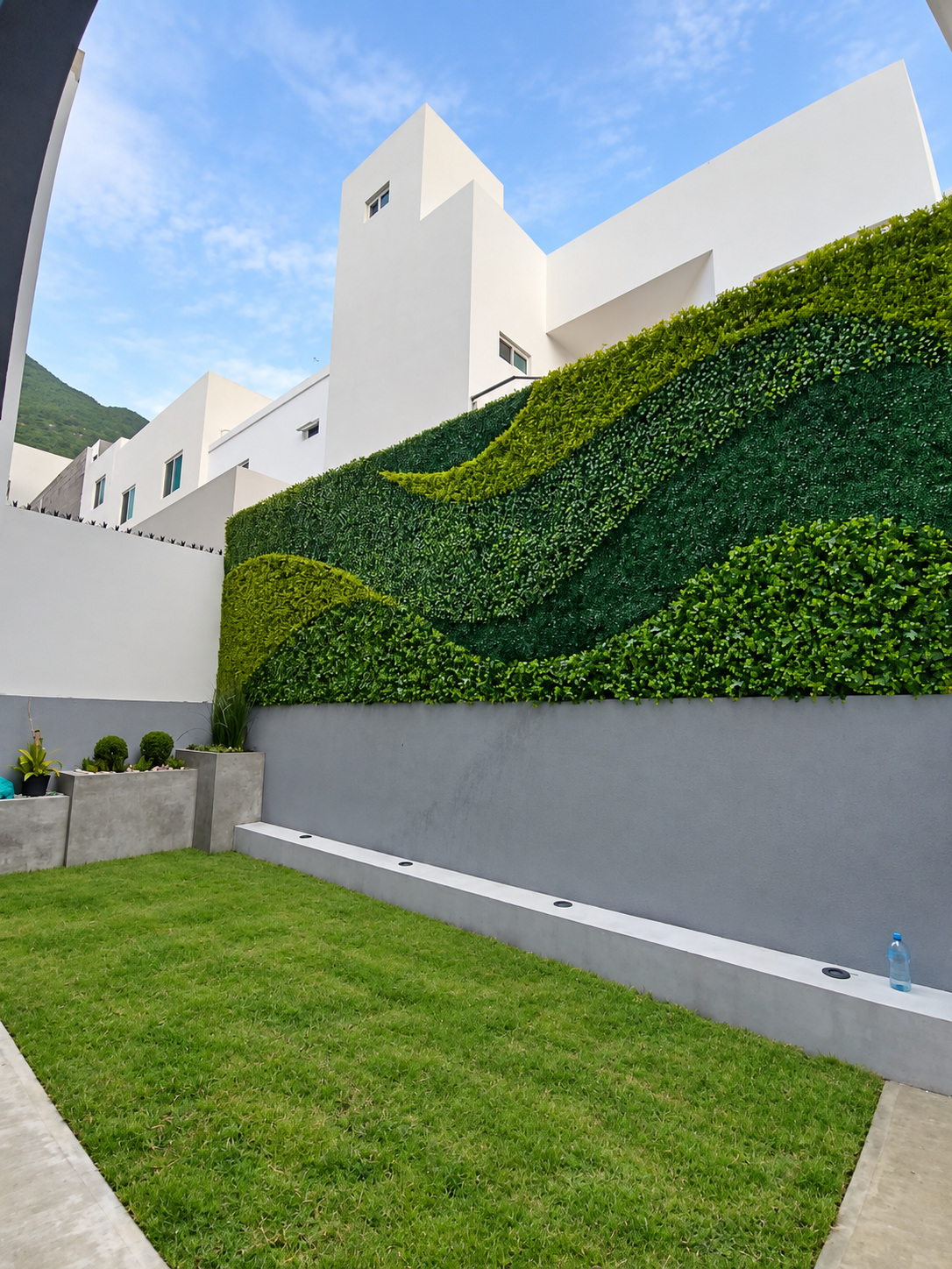 Patio con pasto y muro verde de diseño