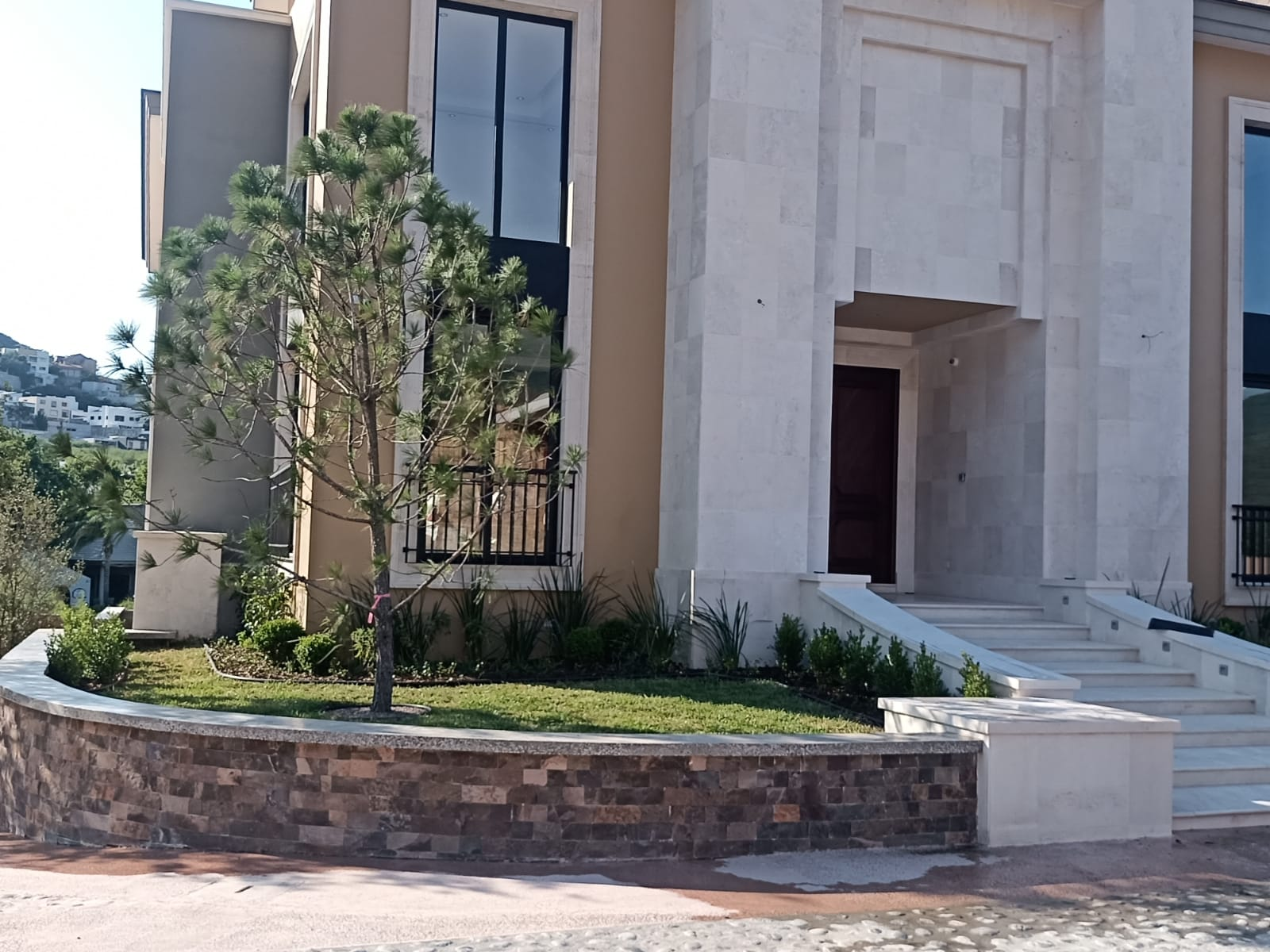 Jardín frontal con árboles y vegetación